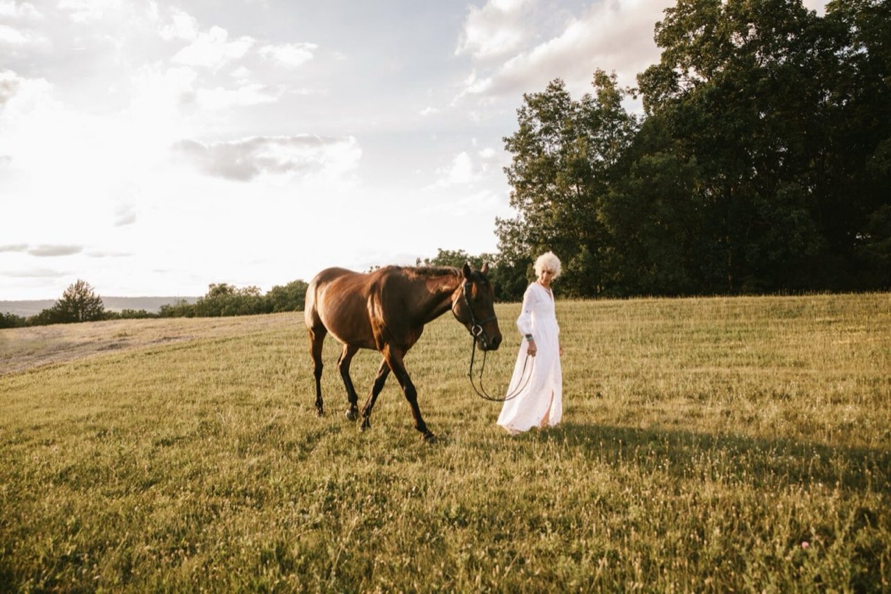 Sasha walking a horse across the pasture at golden hour